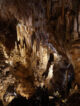 Vue panoramique de la grotte de l'Aven d'Orgnac avec ses stalactites géantes et des visiteurs sur la passerelle.