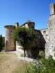 Cour intérieure en pierre du château de Vogüé avec ses tours médiévales sous un ciel bleu.