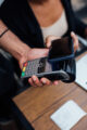 Personne effectuant un paiement sans contact avec son smartphone sur un terminal de carte bancaire