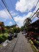 Ruelle piétonne paisible à Ubud avec un étal de fruits tropicaux et des scooters