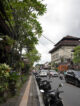 Rue animée du centre-ville d'Ubud avec trottoir, scooters et architecture balinaise