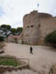 Visiteur marchant devant la tour en pierre du Fort Sainte-Agathe à Porquerolles